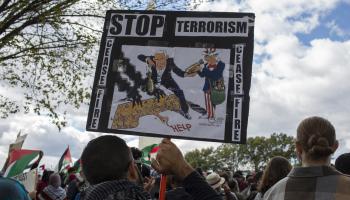 	 متظاهر في واشنطن يرفع كاريكاتير لكارلوس لطّوف (بروبال رشيد / Getty)