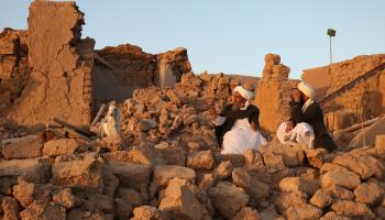 يجلسان على أنقاض الزلزال في هيرات (محسن كريمي/ فرانس برس)
