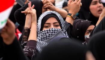 شابة عراقية والكوفية الفلسطينية في تظاهرة سابقة في العراق (حسين فالح/ فرانس برس)
