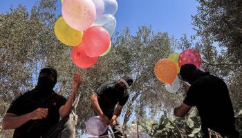 فلسطينيون ملثمون يستعدون لإطلاق بالونات حارقة بالقرب من السياج الحدودي شرق خان يونس (سعيد خطيب / فرانس برس) 