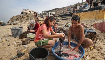 يساعدان في غسل الثياب عند الشاطئ (مصطفى حسونة/ الأناضول)