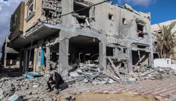 رجل يجلس على أنقاض المباني المدمّرة بسبب القصف الإسرائيلي في خانيونس جنوبيّ قطاع غزّة في 27/ 11/ 2023 (Getty)