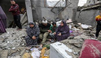 أسرة فلسطينية تجلس على أنقاض منزلها المدمر بسبب القصف الإسرائيلي في رفح جنوب قطاع غزّة في 15/ 11/ 2023 (الأناضول)