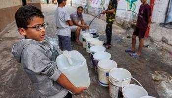 أطفال وتعبئة مياه في غزة (محمد عابد/ فرانس برس)