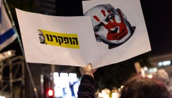 صورة نتنياهو عليها يد ملطخة بالدماء اعتراضاً على سياسة الحكومة (ماجا هيتيج/ Getty)