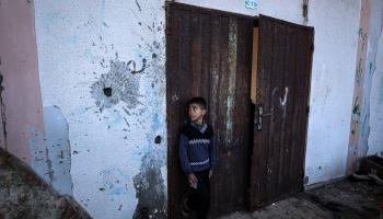 طفل فلسطيني ينظر إلى آثار دمار القصف الإسرائيلي في جدار ملجأه، رفح، 29 كانون الأول/ ديسمبر 2023 (Getty) 