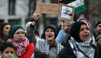 متظاهرة في برلين ترفع لافتة: ألمانيا متواطئة (مريم ماجد/Getty)