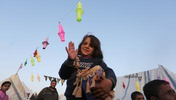 أطفال يُعلّقون "فوانيس رمضان" بين خيام النازحين في دير البلح، 10 آذار/ مارس 2024 (Getty)
