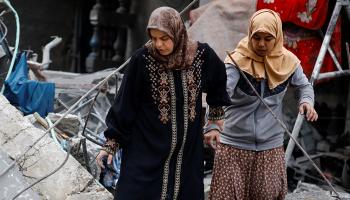 فلسطينيتان تتفقدان آثار غارة إسرائيلية على رفح، أمس (محمد سالم/رويترز)