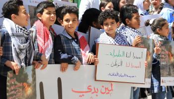 أطفال فلسطينيون يحملون لافتات في "يوم الطفل العالمي"، الخليل، 4 نيسان/ إبريل 2024 (Getty)