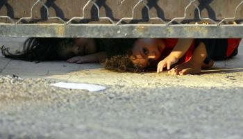طفلان عراقيان يُطلّان من أسفل باب منزل في بغداد