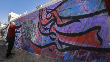 الفنان باسل المقوسي في رفح يُنجز جدارية حروفية (محمد عابد / فرانس برس)