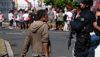 شرطي ومواطن خلال أزمة كاليدونيا الجديدة في نوميا، 18 مايو (ثيو روبي/فرانس برس)