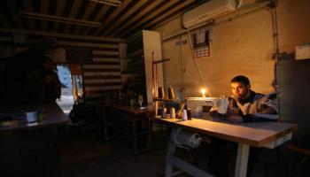 فلسطيني يعمل على ضوء الشموع