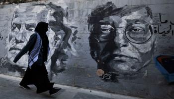 امرأة تنظر إلى غرافيتي في الأردن/مجتمع (أرتور فيداك/ Getty)