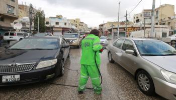 عمّال بلدية عمّان يعقمون السيارات في مارس(خليل مزرعاوي/فرانس برس)