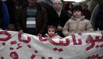 عائلة سورية لاجئة أمام مبنى برلمان اليونان (فرانس برس)