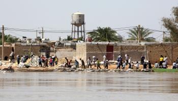 إيرانيون يحاولون صد الفيضان في خوزستان (عطا كينار/فرانس برس)