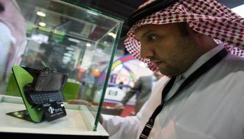 سعودي يتفقد هاتف جوال في معرض للاتصالات-فرانس برس