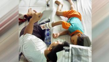 أب ينام أمام سرير إبنه في المستشفى 