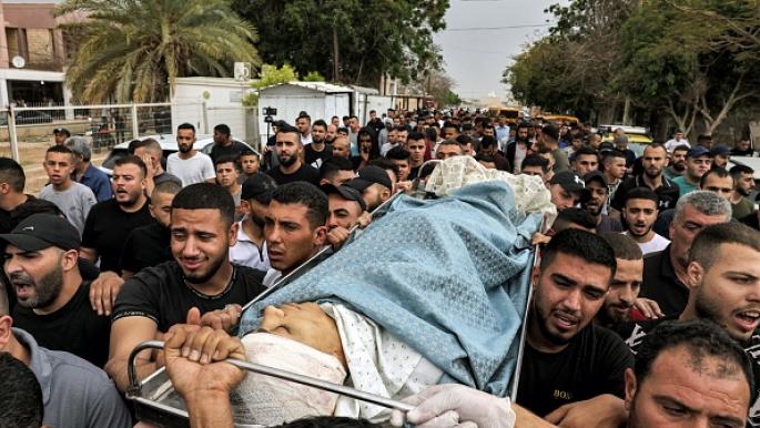 شبان يحملون جثمان الشهيد بلهان قرب مستشفى أريحا (أحمد غرابلي/ فرانس برس)

