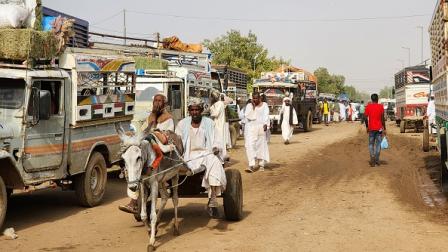 سودانيون يمرون أمام شاحنات في مدينة شندي 21 سبتمبر 2023 (Getty)