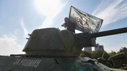 رجل يرفع علم مجموعة فاغنر فوق دبابة في دونيتسك 1 أكتوبر 2023 (Getty)