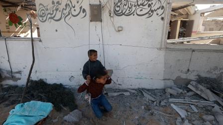 طفلان فلسطينيان يلعبان على أرجوحة وسط الدمار بخانيونس، في 16 يناير 2024 (فرانس برس)