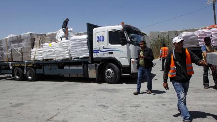 فلسطينيون يفرغون حمولة شاحنات وصلت رفح عبر معبر كرم أبو سالم (فرانس برس)