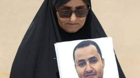 والدة توفيق المنصوري تحمل صورته في اعتصام سابق (تويتر)