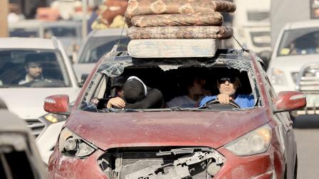 عائلة فلسطينية تستقل مركبة متضررة للنزوح من مناطق القصف (فرانس برس)