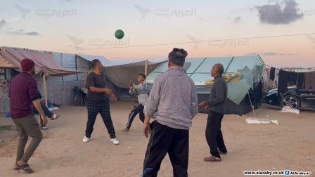 نازحون فلسطينيون يلعبون الكرة الطائرة في المواصي في جنوب غزة (العربي الجديد)