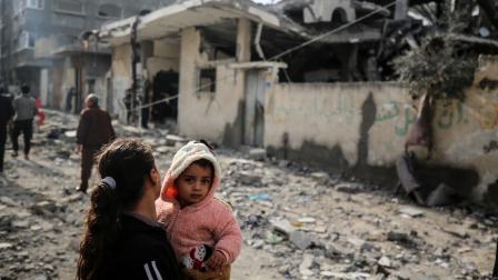 شابة فلسطينية تتفقّد بعد قصف على دير البلح، 12 شباط/ فبراير 2024 (Getty)