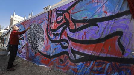 الفنان باسل المقوسي في رفح يُنجز جدارية حروفية (محمد عابد / فرانس برس)