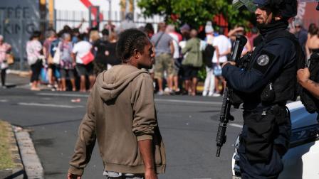 شرطي ومواطن خلال أزمة كاليدونيا الجديدة في نوميا، 18 مايو (ثيو روبي/فرانس برس)