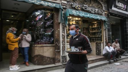 عامل مقهى يضع الكمامة بشارع المعز السياحي بالقاهرة (Getty)