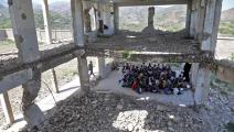 أطفال يمنيون يتلقون الدروس داخل مدرستهم المدمّرة في تعز (فرانس برس)