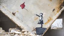 عمل لفنان مجهول الهوية على جدار منزّل مدمّر، في إدلب، 7 آذار/ مارس 2022 (Getty)